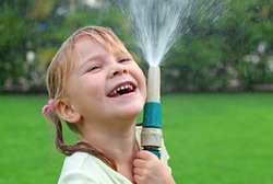 Happy Girl Pours Water From A Hose