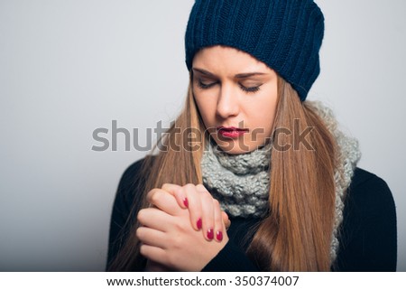 happy girl praying, winter concept, studio photo isolated on a gray background