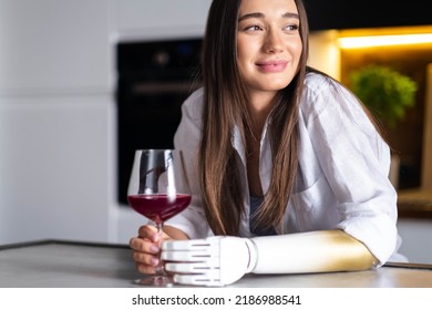 Happy Girl With Prosthetic Arm Holds Glass Of Wine In Artificial Prosthetic Limb Hand At Home