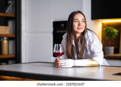 Happy Girl With Prosthetic Arm Holds Glass Of Wine In Artificial Prosthetic Limb Hand At Home