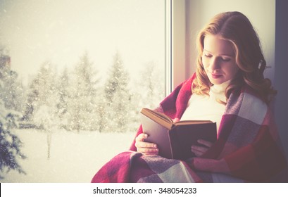 happy girl reading a book by the window in the winter - Shutterstock ID 348054233