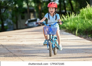 Happy girl riding a bike in garden park . Active child wearing bike helmet. Safety sports leisure with kids concept