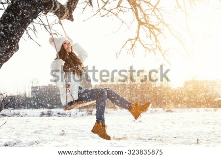 Happy girl and rope swing at sunny winter day