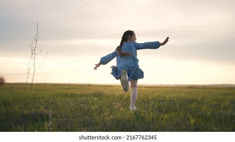 Happy girl run on green grass in park. Cheerful child in meadow in the park in sun. Girl running summer joy outdoors. The child plays on the spring grass quick run of girl at sunset in garden of park - Powered by Shutterstock