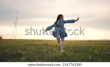 Happy girl run on green grass in park. Cheerful child in meadow in the park in sun. Girl running summer joy outdoors. The child plays on the spring grass quick run of girl at sunset in garden of park