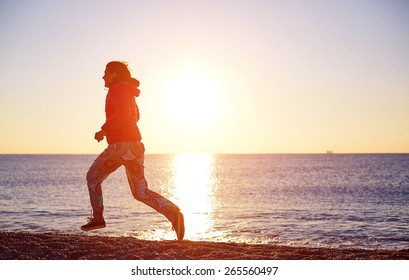 happy girl running on the beach at sunrise against the sun. silhouette