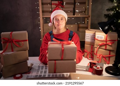 Happy Girl Santa Claus Packing Present Box Wrapping Gift Preparing Post Shipping Delivery Parcel On Table In Workshop At Night. Merry Christmas Shipping Delivery Concept.