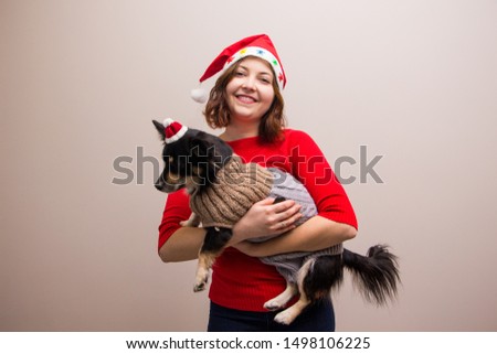 Happy girl in santa hat in red blouse with little black dog