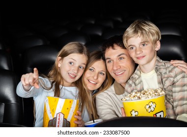 Happy Girl Showing Something To Family While Watching Movie In Cinema Theater