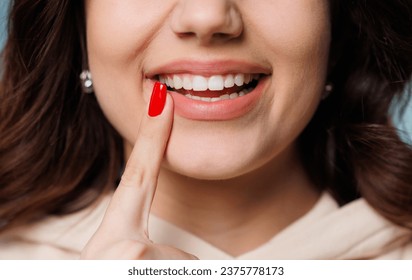 Happy girl showing toothy smile, pointing finger at healthy white teeth. Clinic patient satisfied with dentist service, enamel cleaning, whitening, dental care, correction. Cropped shot, close up - Powered by Shutterstock