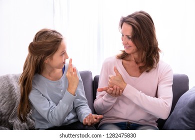 Happy Girl Sitting On Sofa Learning Sign Languages From Woman - Powered by Shutterstock