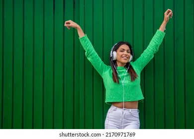 Happy Girl Smiling With Mobile Phone And Earphones In The Street Dancing