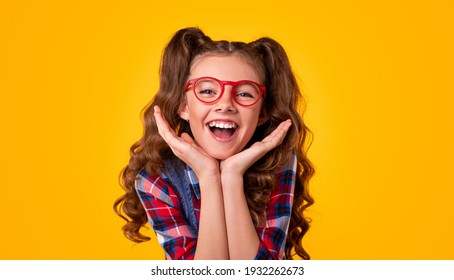 Happy girl in stylish glasses and checkered shirt touching face and looking at camera against yellow background - Shutterstock ID 1932262673