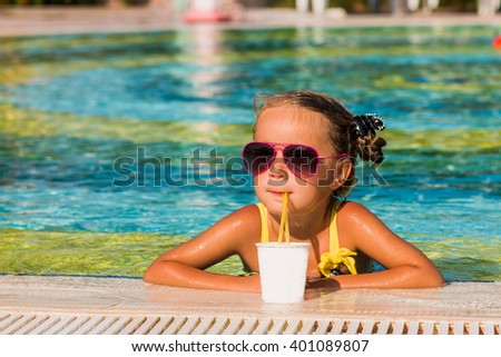 Happy girl in sunglasses drink juice in the pool
