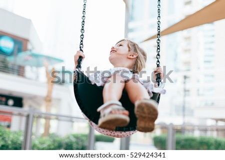 Happy girl swinging outdoors on the playground