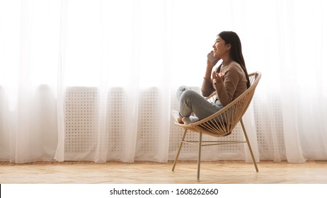 Happy girl talking on phone, sitting in modern armchair near window, panorama with copy space - Shutterstock ID 1608262660