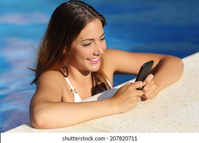 Happy Girl Using A Smart Phone White Bathing In A Swimming Pool In Summer Vacations With Blue Water In The Background