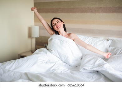 Happy girl waking up stretching arms on the bed in the morning - Shutterstock ID 685618564
