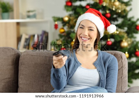 Happy girl watching tv in christmas sitting on a couch in the living room at home