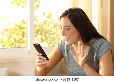 Happy Girl Waving During An On Line Phone Video Call At Home