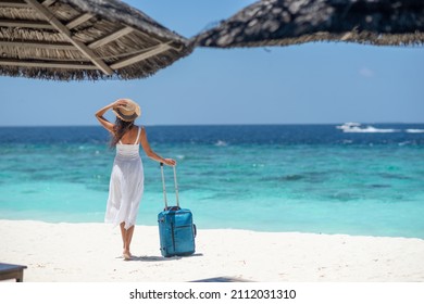 Happy girl in white dress and hat holding suitcase on the beach - Powered by Shutterstock