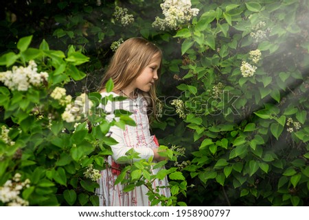 Happy girl in a white dress in lilac flowers in spring, selective focus
