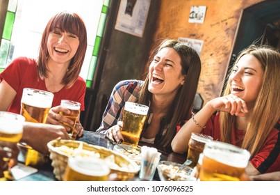 Happy girlfriends women group drinking beer at brewery bar restaurant - Friendship concept with young female friends enjoying time and having genuine fun at cool vintage pub - Focus on left girl - Powered by Shutterstock