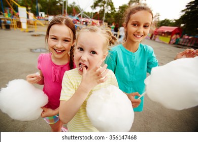 Happy girls eating cotton candy in the park