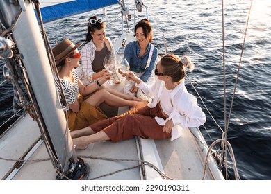 Happy girls friends drinking white wine on the sailboat during sailing in the sea. - Powered by Shutterstock