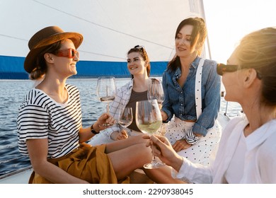 Happy girls friends drinking white wine on the sailboat during sailing in the sea. - Powered by Shutterstock