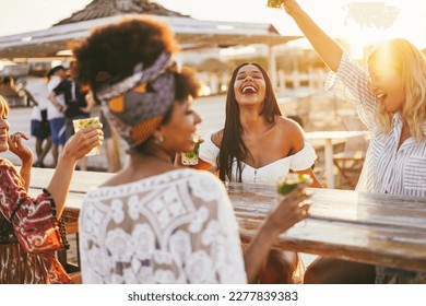 Happy girls having fun drinking cocktails at bar on the beach - Party and summer concept - Focus on latin girl face