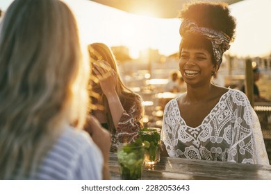 Happy girls having fun drinking cocktails at bar on the beach - Soft focus on african girl face - Powered by Shutterstock