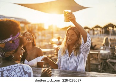 Happy girls having fun drinking cocktails at bar on the beach - Soft focus on african girl face