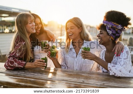 Happy girls having fun drinking cocktails at bar on the beach - Soft focus on center blond girl face