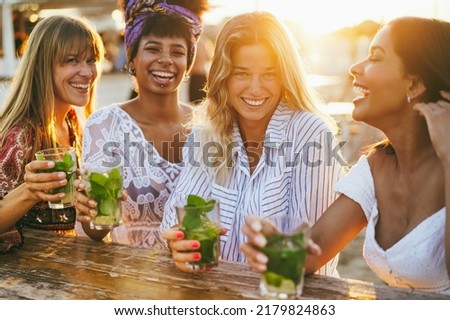 Happy girls having fun drinking cocktails at bar on the beach - Soft focus on right blond girl face