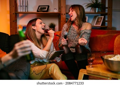 Happy Girls Sitting At Home And Singing A Duet. Karaoke Night.