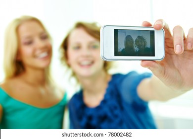 Happy girls taking photo of themselves on telephone camera