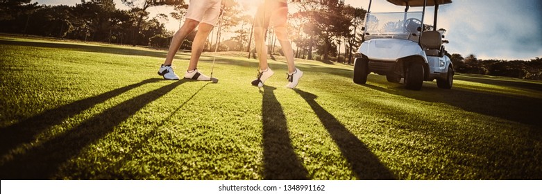 Happy golf player couple giving high five while standing on field - Powered by Shutterstock