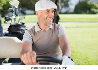 Happy golfer driving his golf buggy on a sunny day at the golf course