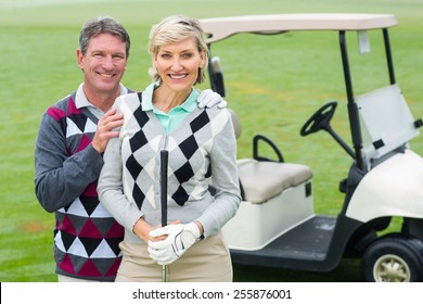 Happy Golfing Couple With Golf Buggy Behind On A Foggy Day At The Golf Course