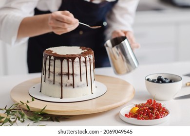 Happy good looking female pastry chef standing with her cake while making. Putting cream on a birthday cake. High quality photo - Powered by Shutterstock