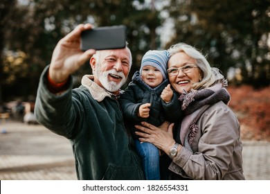 Happy good looking senior couple husband and wife walking and playing with their adorable grandson in public city park - Powered by Shutterstock