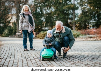 Happy good looking senior couple husband and wife walking and playing with their adorable grandson in public city park - Powered by Shutterstock