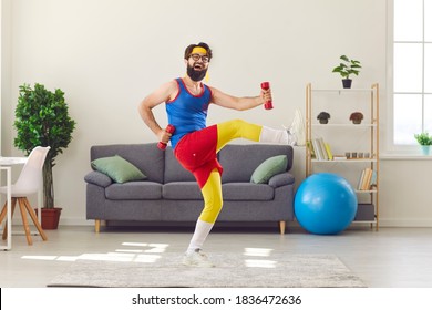 Happy goofy young man in retro sportswear decided to start fitness training and now is exercising with dumbbells and laughing, motivating you to do sports, keep fit and lead healthy lifestyle too
