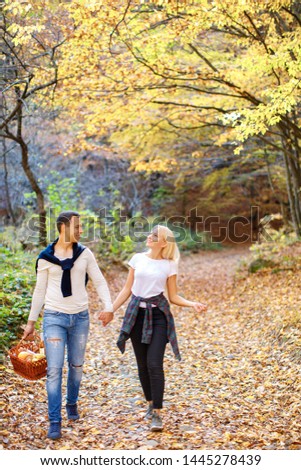 Happy gorgeous couple go for a walk in the forest for picnic with basked. beautiful man and woman in the autumn forest for vacation. active weekend for couple. couple pick up mushrooms. engagement 