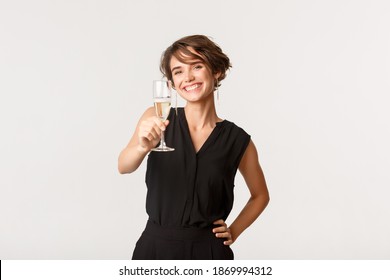 Happy Gorgeous Girl Making Toast, Raising Glass Of Champagne And Smiling, Congratulating Someone, Standing Over White Background