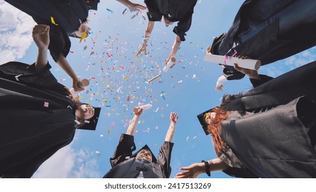Felices graduados lanzando confetti colorido contra el cielo azul del verano.