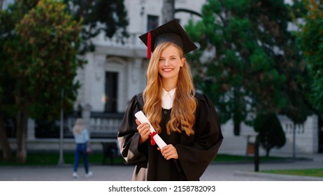 Happy graduation day for a young woman very beautiful with graduation cap smile large in front of the Camera posing while holding her diploma