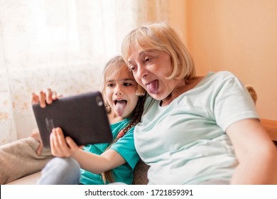 Happy grandchild teaching her grandma to use portative tablet and make selfie, online life, new normal after coronavirus pandemic, happy silver surfer an digital native generation