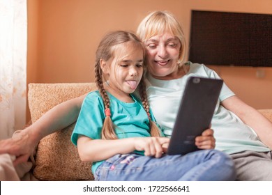 Happy grandchild teaching her grandma to use portative tablet and make selfie, online life, new normal after coronavirus pandemic, happy silver surfer an digital native generation